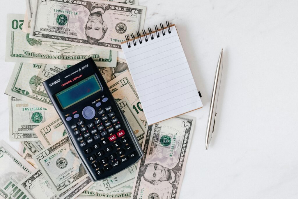 Flat lay of US dollar bills with calculator and notebook for budgeting.